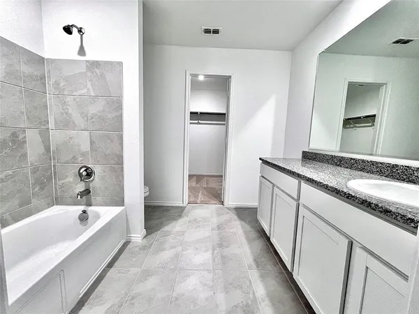 a bathroom with a granite countertop tub sink and mirror