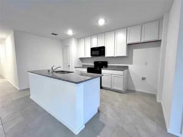 a kitchen with kitchen island a sink a stove a refrigerator a counter top space and cabinets