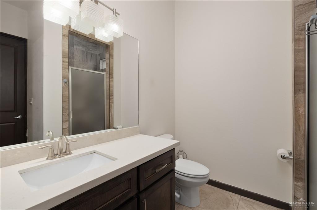 2615 South 43 Rd Lane McAllen, TX 78503 - Photo 12 of 22 a bathroom with a sink a toilet a mirror and vanity