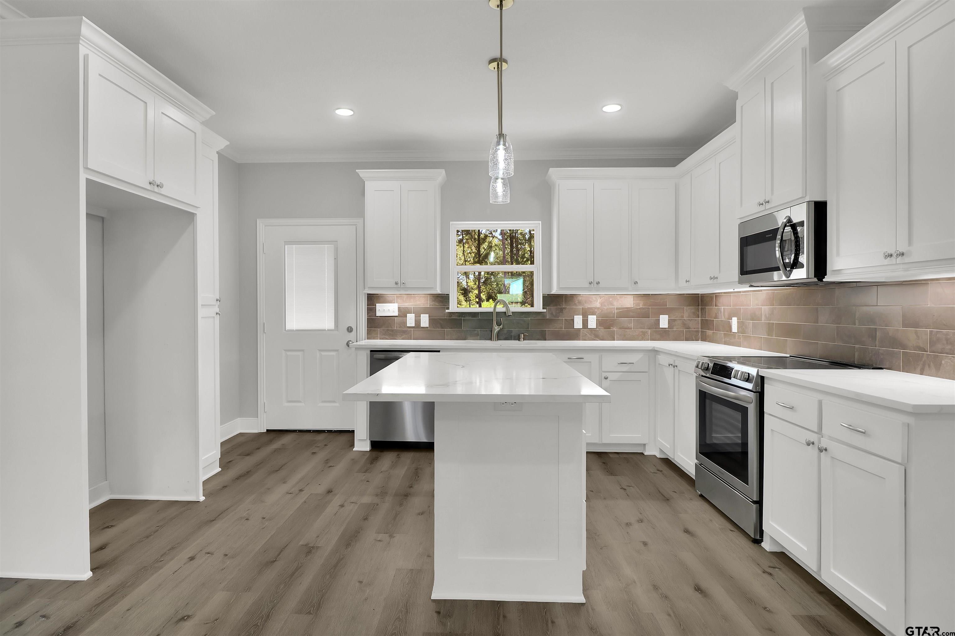 614 North Commerce Street Overton, TX 75684 - Photo 6 of 24 a kitchen with kitchen island granite countertop a sink cabinets and wooden floor