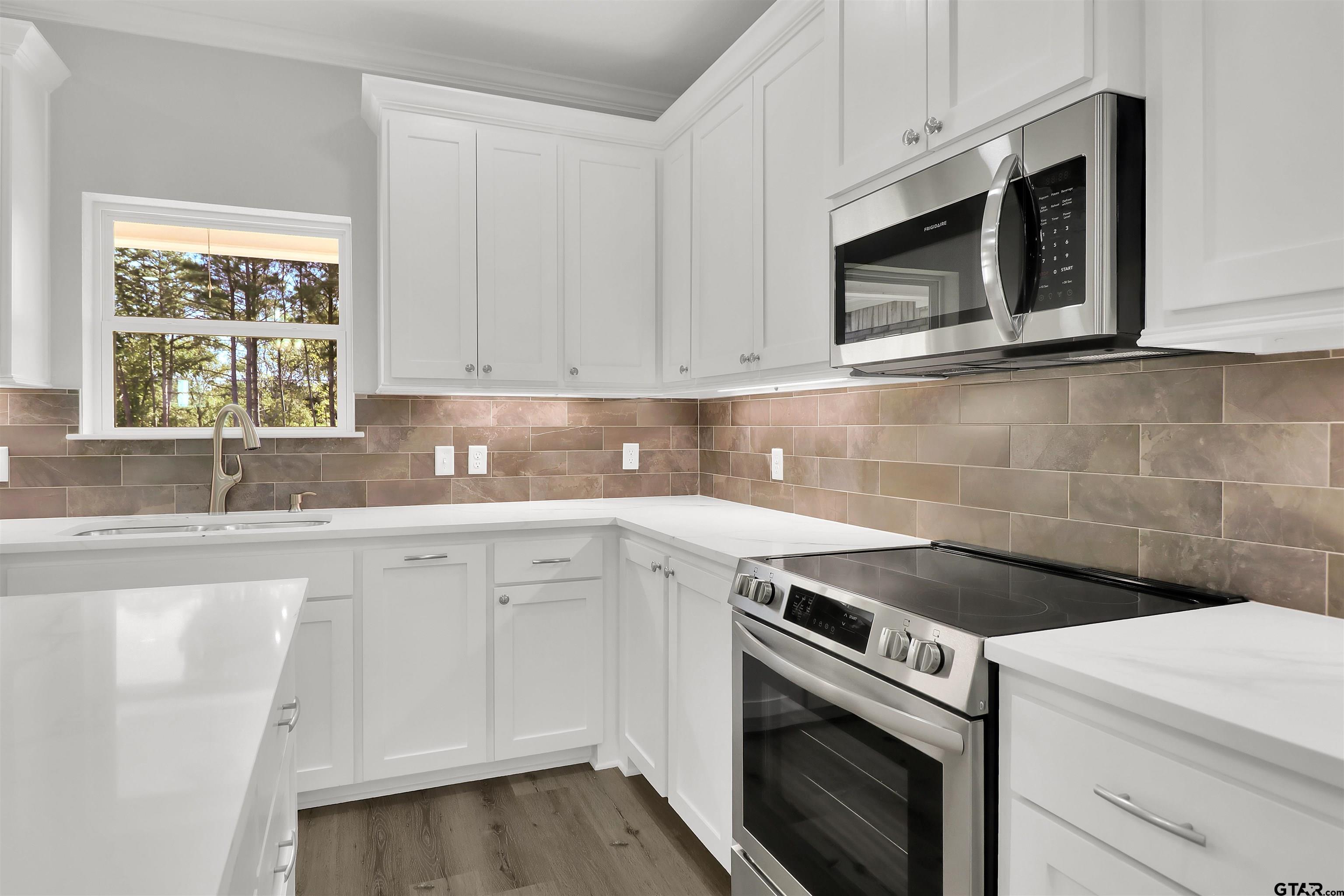 614 North Commerce Street Overton, TX 75684 - Photo 8 of 24 a kitchen with granite countertop white cabinets stainless steel appliances and sink