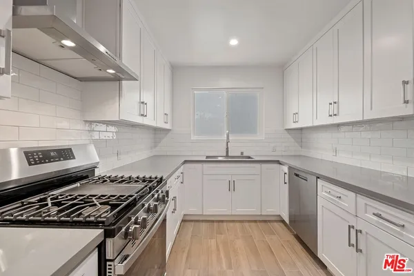 a kitchen with granite countertop a stove sink and cabinets