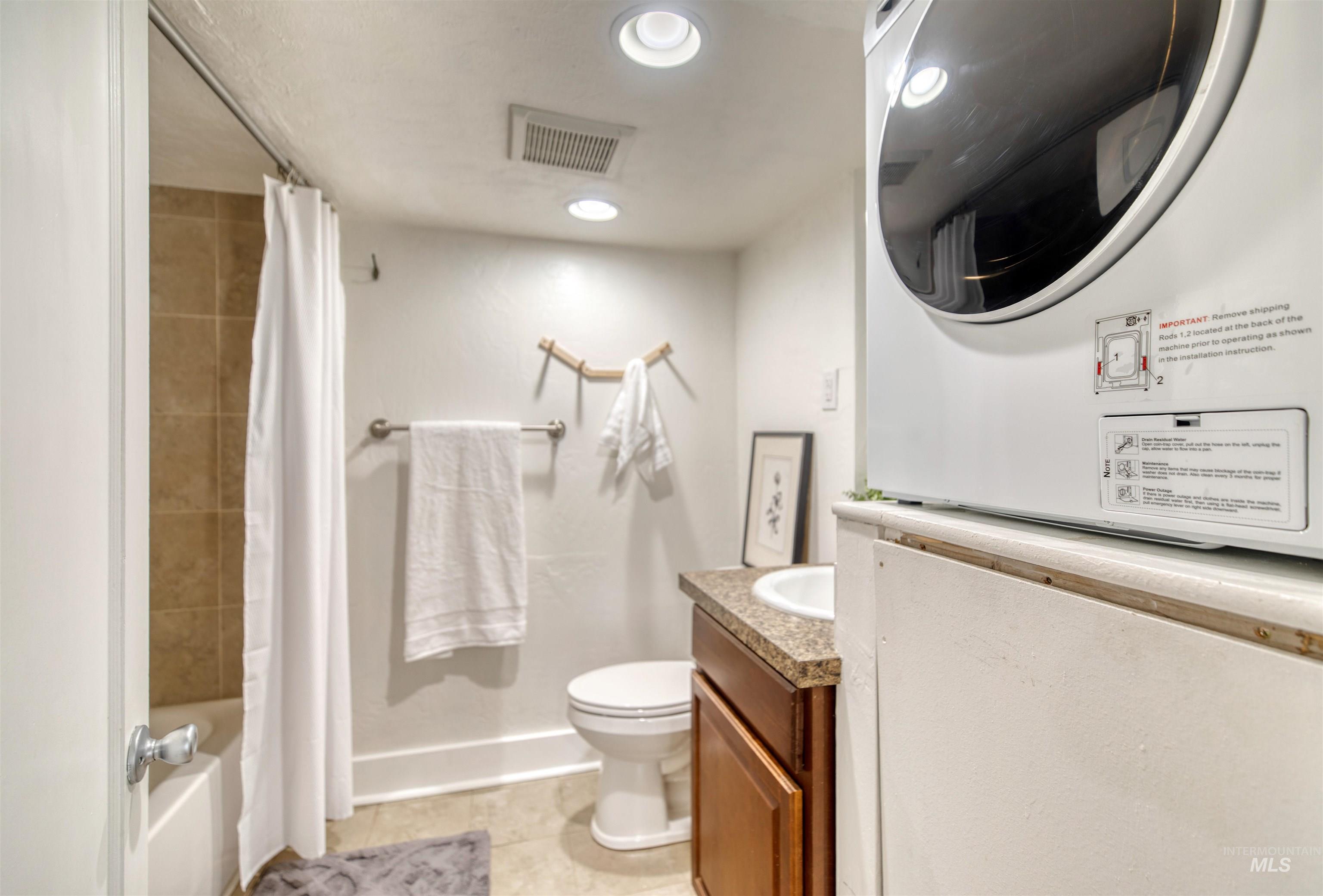 3311 West Hamilton Street Boise, ID 83705 - Photo 10 of 32 Full bathroom with light tile patterned floors, shower / bath combo with shower curtain, estacked washer and dryer, vanity, and recessed lighting