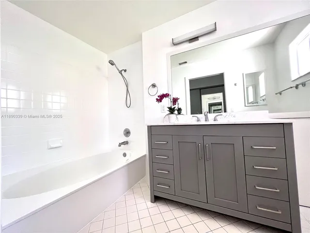 a bathroom with a tub a double vanity sink and mirror