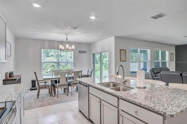 a dining hall with stainless steel appliances granite countertop a barbecue tub and large windows