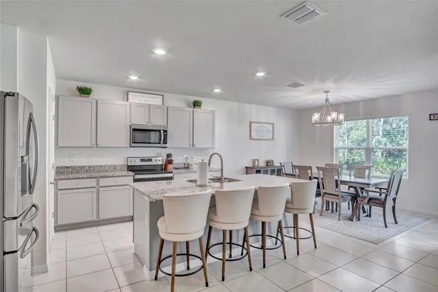 a large kitchen with kitchen island granite countertop a dining table chairs and white cabinets