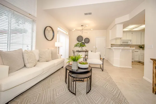 a living room with stainless steel appliances furniture a rug and a kitchen view