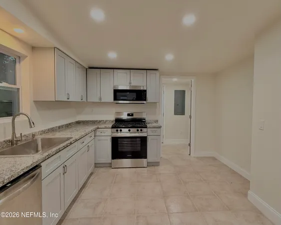 a kitchen with kitchen island granite countertop a sink and steel appliances