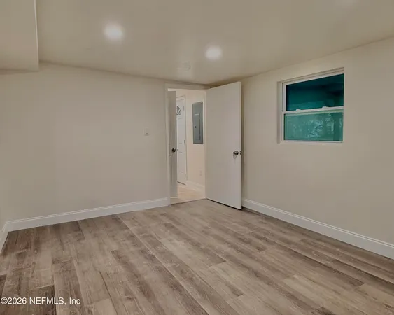 a view of an empty room with wooden floor and closet