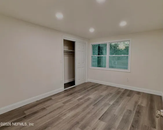 an empty room with wooden floor and windows