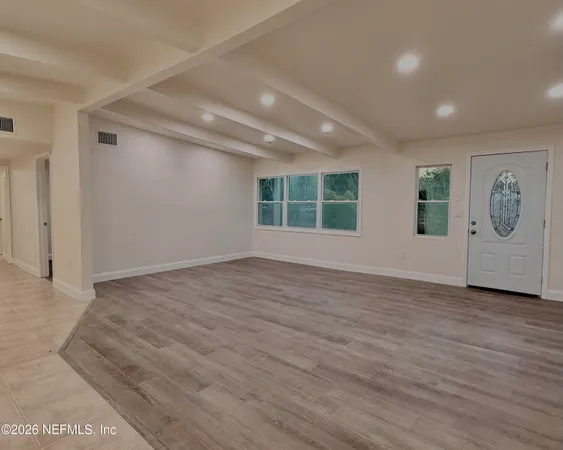 an empty room with wooden floor and mirror