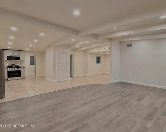 an empty space with kitchen view and wooden floor