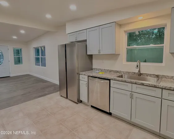 a kitchen with granite countertop white cabinets white appliances and sink