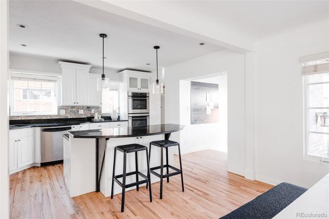 a kitchen with stainless steel appliances granite countertop a stove a sink dishwasher and a refrigerator with wooden floor