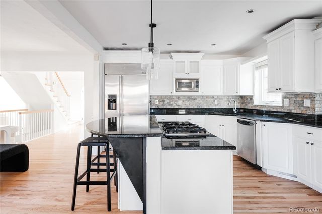 a kitchen with stainless steel appliances kitchen island granite countertop a stove a sink and a refrigerator