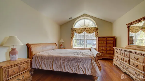 a bedroom with a bed a dresser next to a window