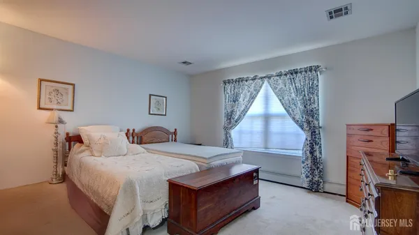 a bedroom with a bed and a flat tv screen on the dresser