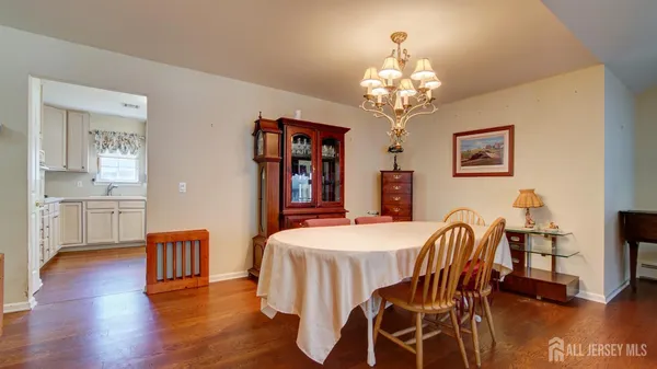 a dining room with wooden floor a chandelier a wooden table and chairs