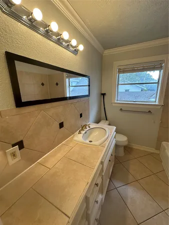 a bathroom with a granite countertop sink a toilet and mirror