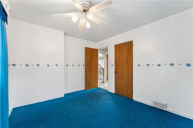 an empty room with closet and a ceiling fan