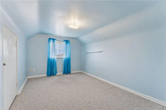 a view of an empty room with closet and a window