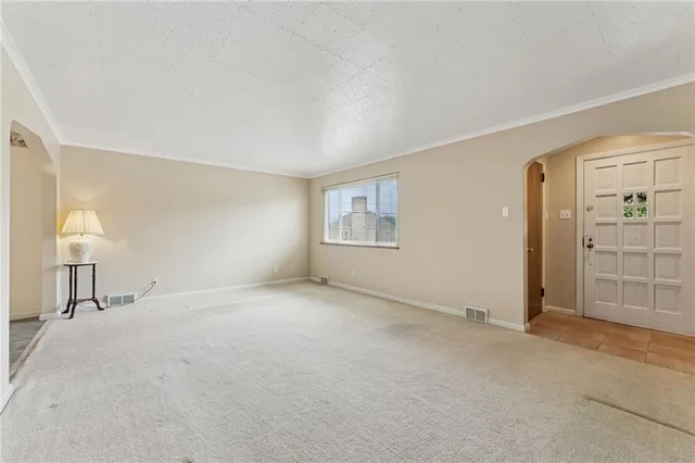 a view of an empty room with cabinet and windows