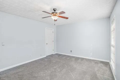 an empty room with a window and a fan