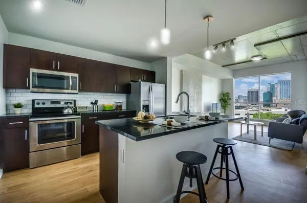 a kitchen with stainless steel appliances granite countertop a stove top oven a sink dishwasher a dining table and chairs with wooden floor
