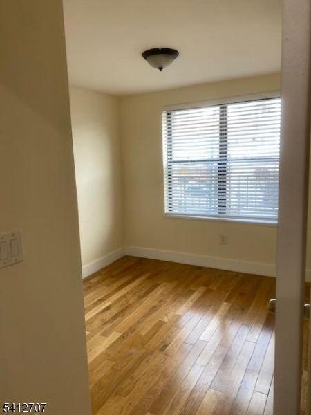 73 Ferry Street Newark, NJ 07105 - Photo 5 of 6 a view of an empty room with wooden floor and a window