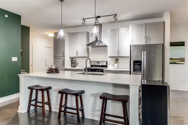 a kitchen with stainless steel appliances a table chairs refrigerator and microwave