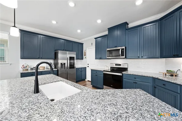 a kitchen with granite countertop a stove sink microwave and refrigerator