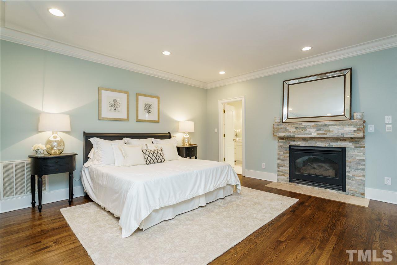 7628 Rainwater Road Raleigh, NC 27615 - Photo 16 of 25 a bedroom with a large bed and a fireplace