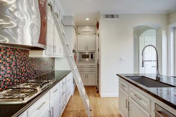 a kitchen with white cabinets and black appliances