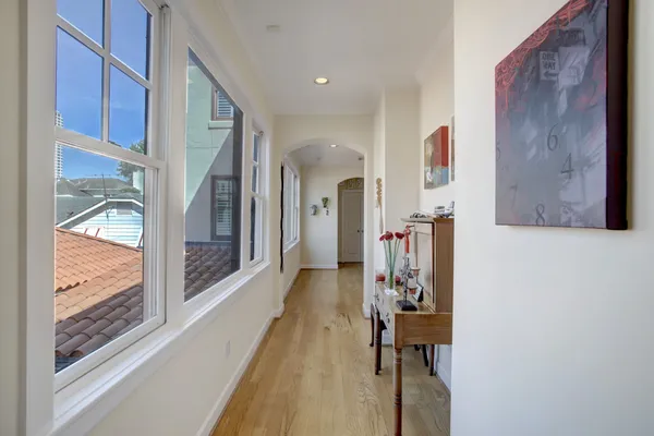 a view of a hallway with wooden floor and windows