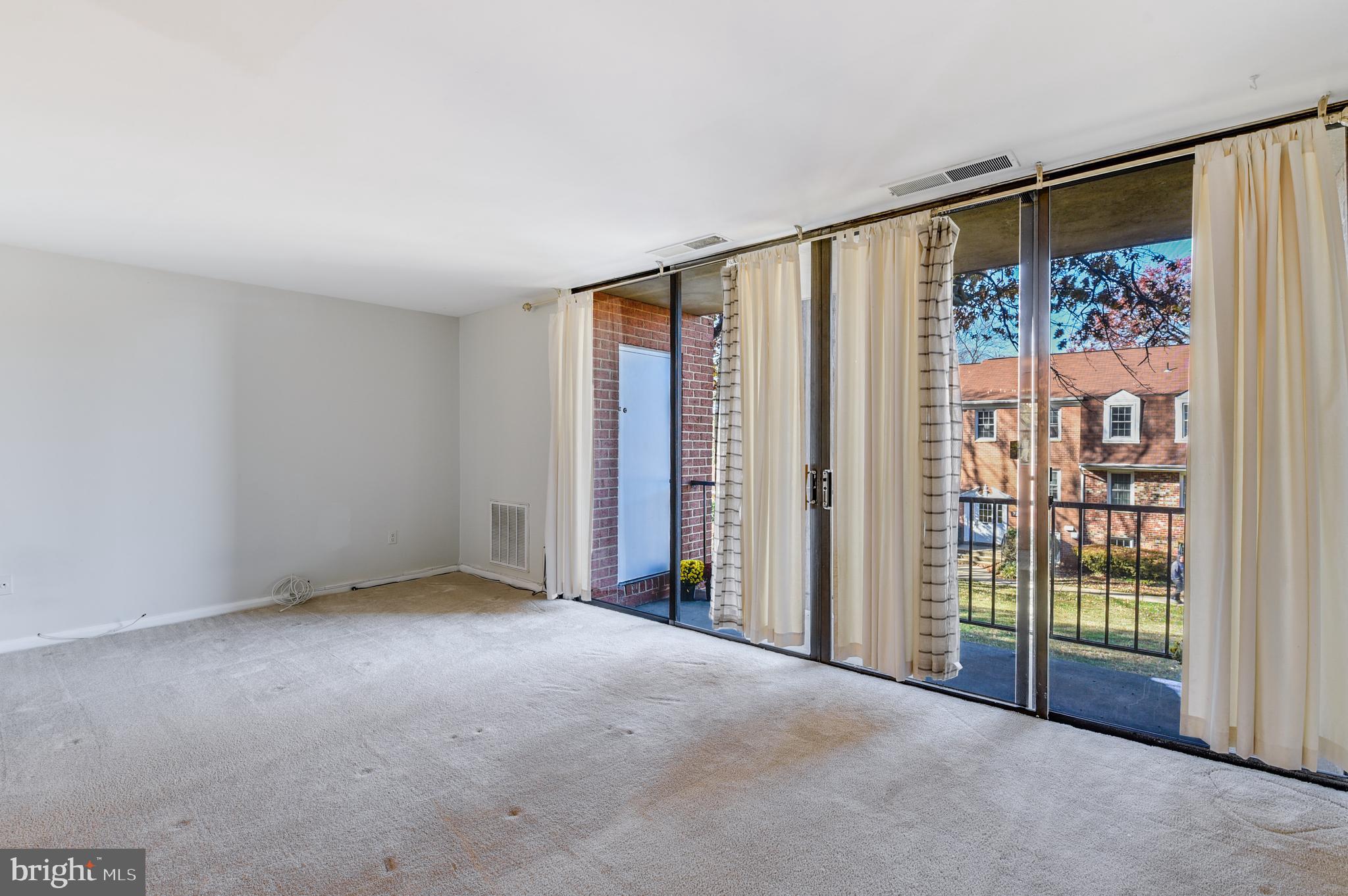 762 Quince Orchard Boulevard, Unit 101 Gaithersburg, MD 20878 - Photo 4 of 21 an empty room with sliding door and tree in a room