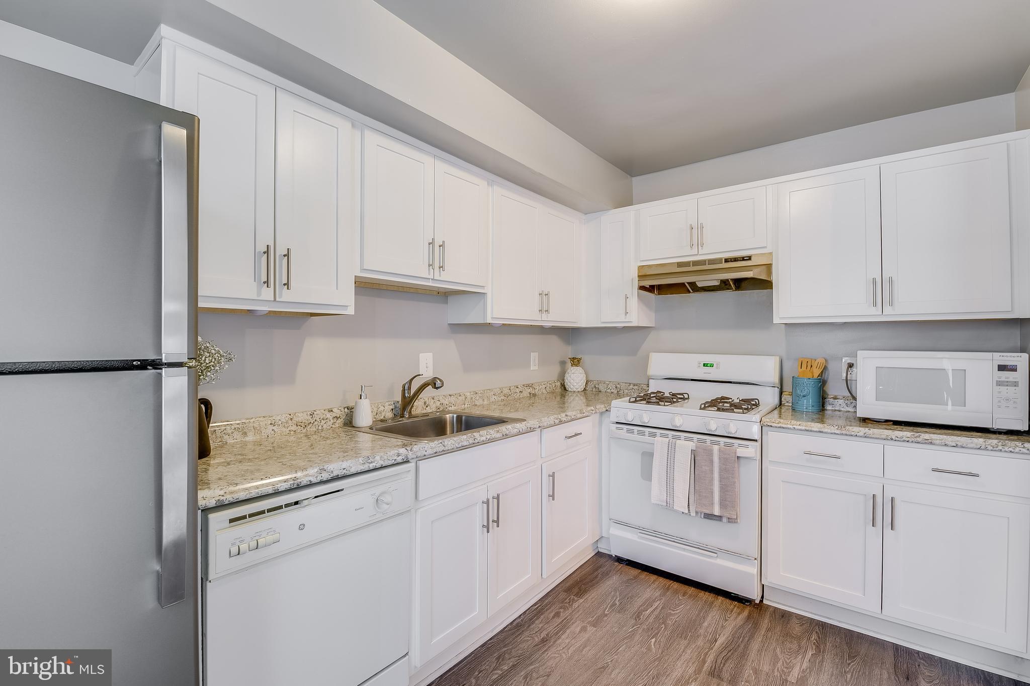 762 Quince Orchard Boulevard, Unit 101 Gaithersburg, MD 20878 - Photo 6 of 21 a kitchen with kitchen island granite countertop white cabinets white appliances and sink