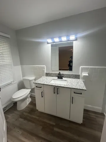 a bathroom with a granite countertop toilet sink and mirror