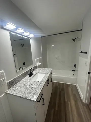a bathroom with a granite countertop sink a toilet and bathtub