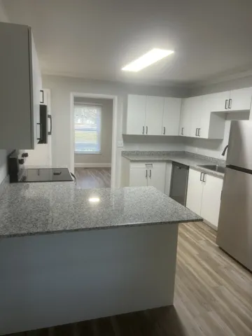 a kitchen with kitchen island granite countertop a sink a counter space and cabinets