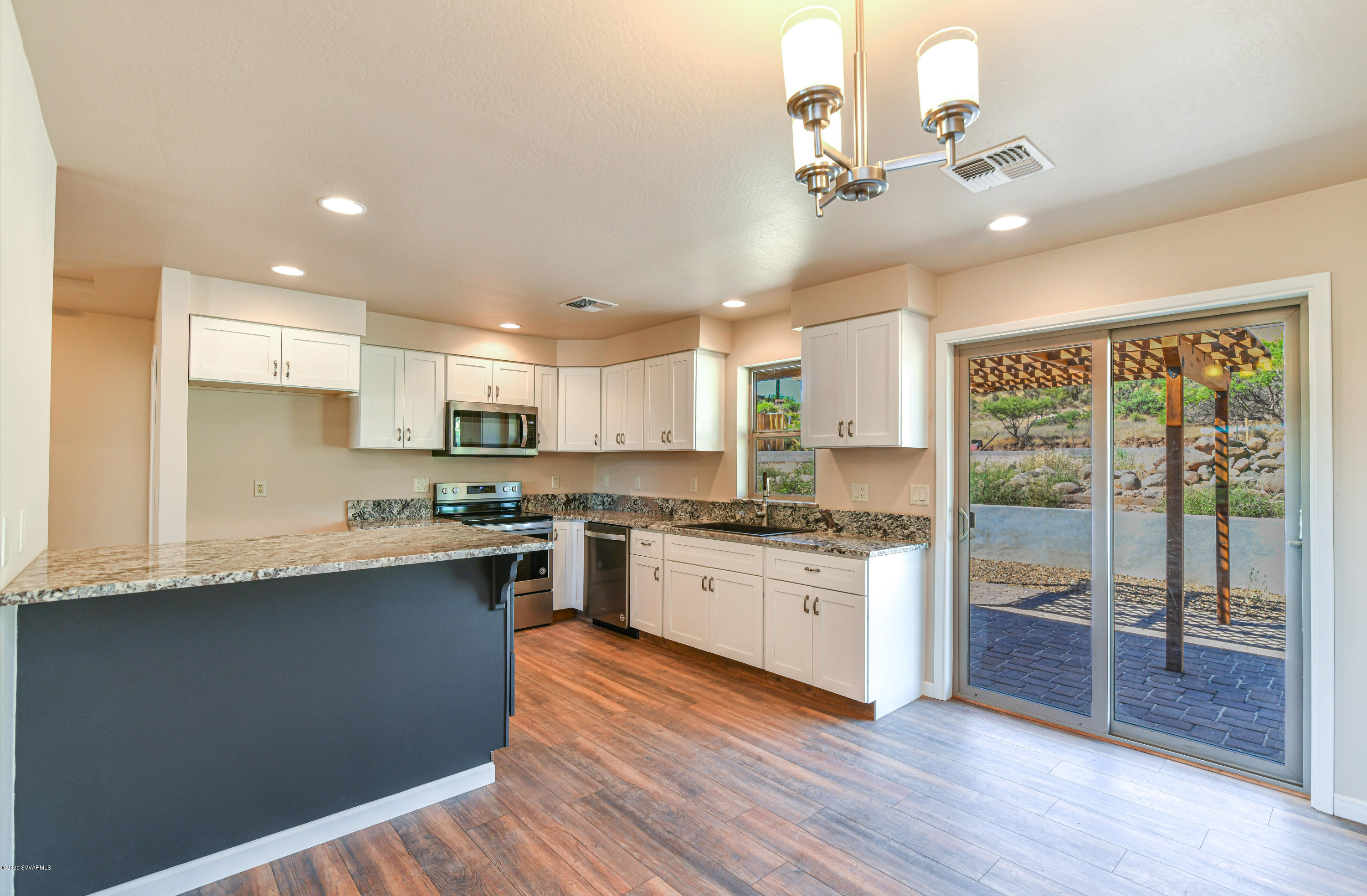 4645 East Goldmine Road Rimrock, AZ 86335 - Photo 5 of 24 a large kitchen with stainless steel appliances granite countertop a stove a refrigerator a sink dishwasher and a dining table with wooden floor