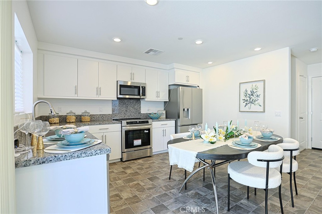 7486 Olive Grv Street Riverside, CA 92507 - Photo 15 of 57 a kitchen with a dining table chairs stove and refrigerator
