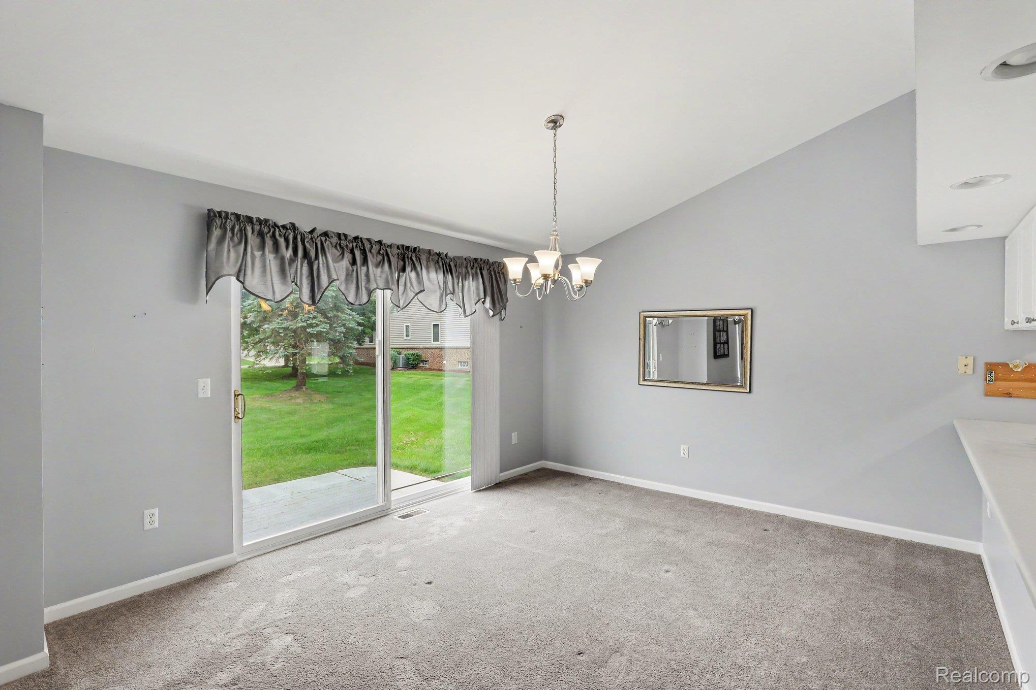 34917 Chickadee Ridge Richmond, MI 48062 - Photo 11 of 32 Vaulted ceiling, sliding glass door, recessed lighting, carpet flooring, and a chandelier