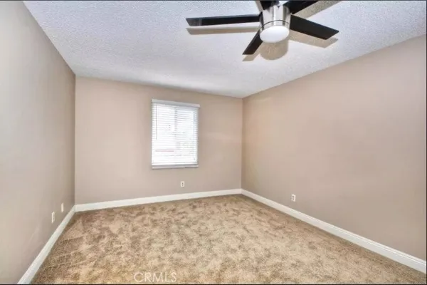 an empty room with chandelier fan and windows