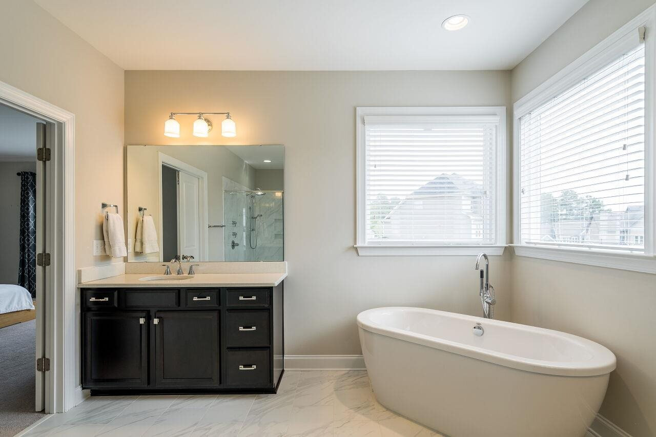 5264 Aleppo Lane Raleigh, NC 27613 - Photo 20 of 30 Soaking tub with freestanding faucet, separate sink vanities, subway tiled shower, separate water closet, and huge walk in closet that leads to laundry room. Owner's Bath