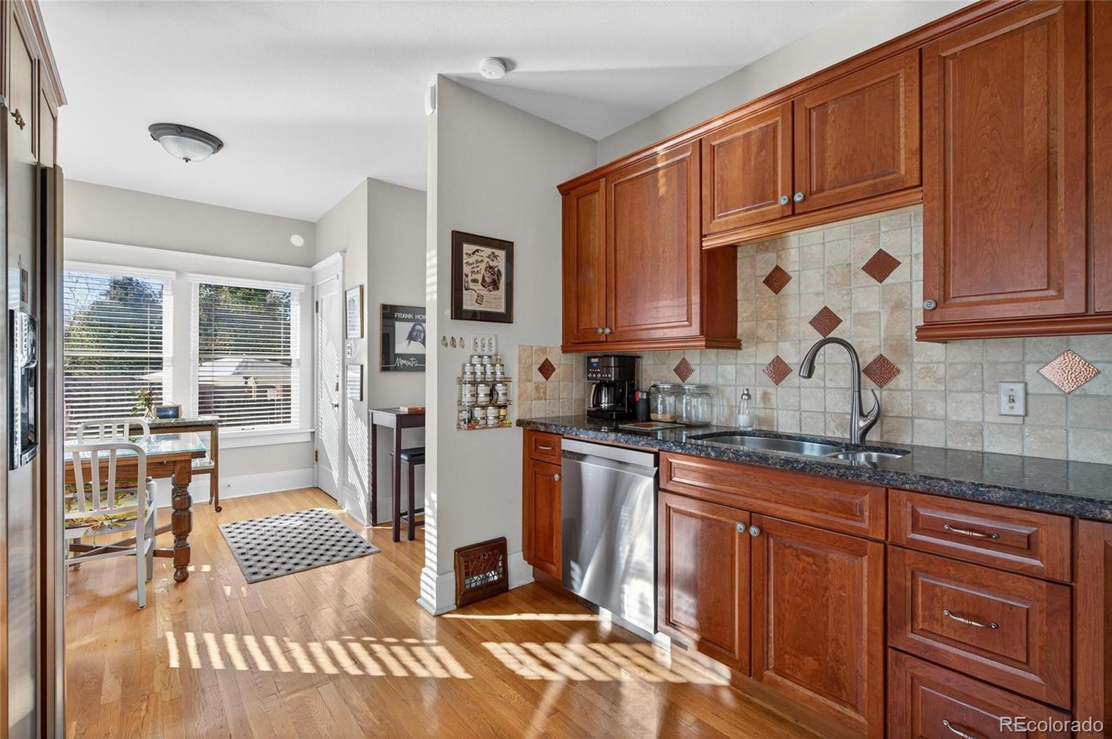 607 Madison Street Denver, CO 80206 - Photo 22 of 31 a kitchen with stainless steel appliances granite countertop a refrigerator and wooden cabinets