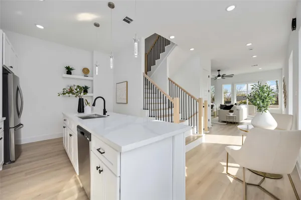 a kitchen with sink a refrigerator and chairs