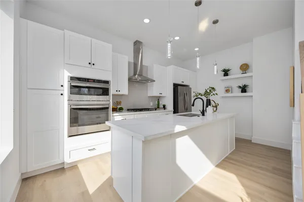 a view of a kitchen with kitchen island a sink stainless steel appliances and cabinets
