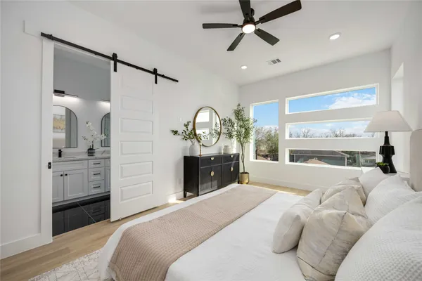 a bedroom with a bed a chandelier and a large mirror on the dresser
