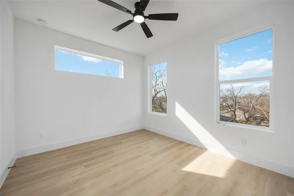 a view of empty room with wooden floor and fan