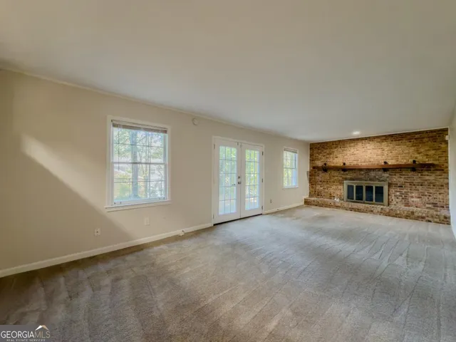 an empty room with windows and fireplace